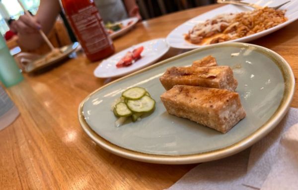 Two pieces of tofu karaage sit on a plate next to a small pile of pickles. This meal is part of the Ricker Dining Specials.