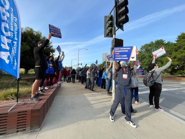 Nurses hold signs in front of Stanford Hospital