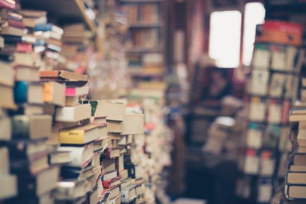 A room filled will stacks of books, some in focus while others are not.