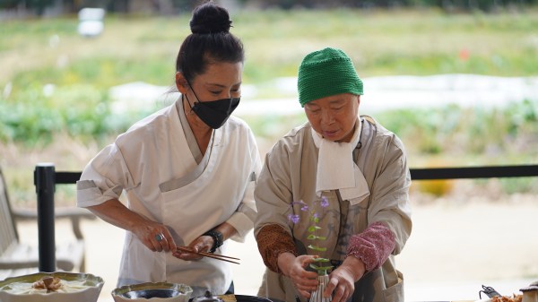 Two people standing next to each other with a green field in the background.