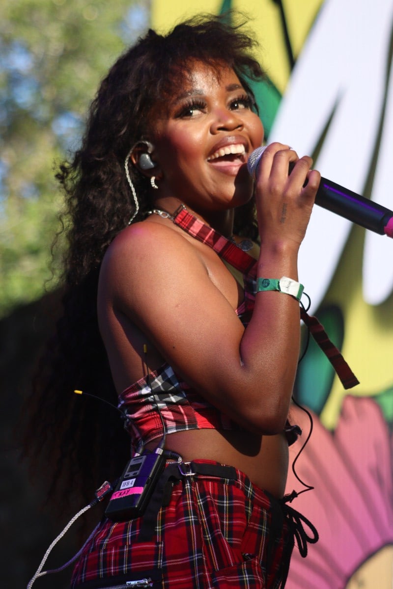 tkay maidza singing with a smile on her face wearing red plaid outfit, holding microphone on stage