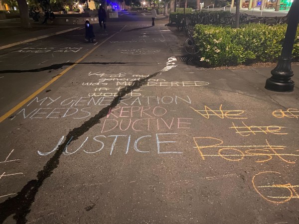 chalk messages are written across the street with water running over them.