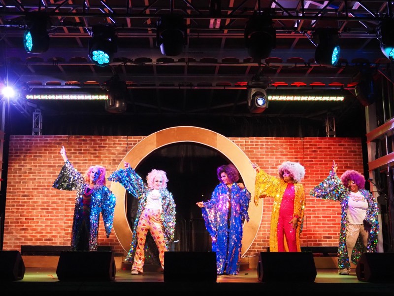 Mona Hicks, Persis Drell, Susie Brubaker Cole, Jeanette Smith-Laws and Shirley Everett wear big, colorful wigs, dramatic makeup and shimmering, sequined robes while dancing to ABBA. 