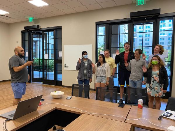 New members of the graduate student council hold their right hands up as they are sworn in.