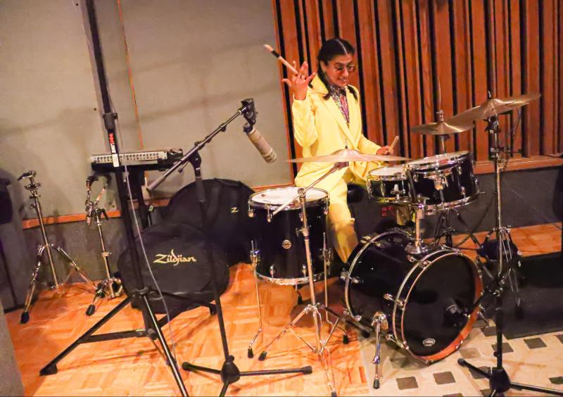 Madame Gandhi spins a drumstick in her hand as she plays on a drumkit