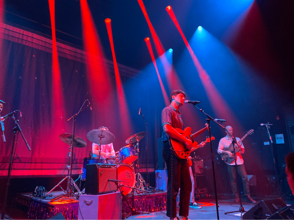 The Dip performing on stage bathed in a red spotlight