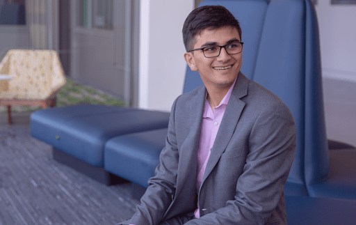 Avi Gupta sitting down wearing a suit and glasses