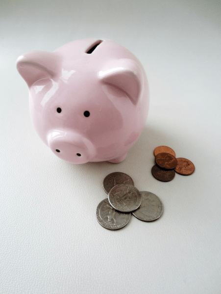 a piggy bank next to a pile of 4 quarters and a pile of 4 pennies