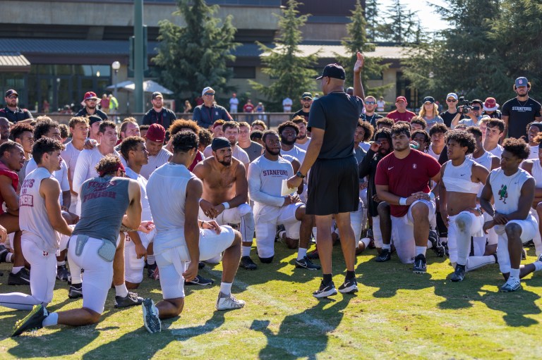 Football players circle up around their head coach.