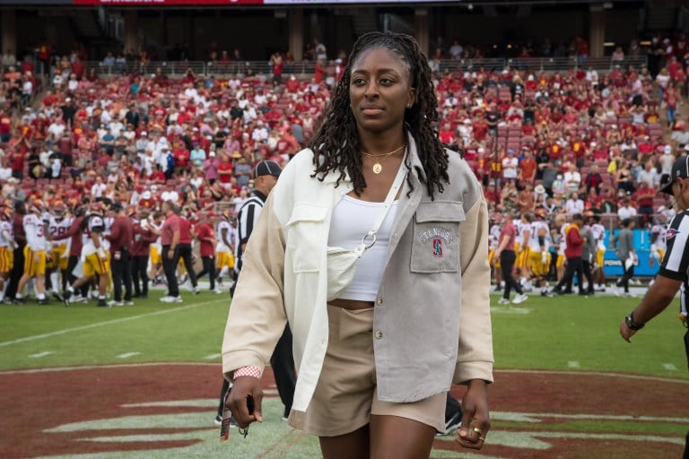 A woman stands in front of the Stanford Stadium crowd.