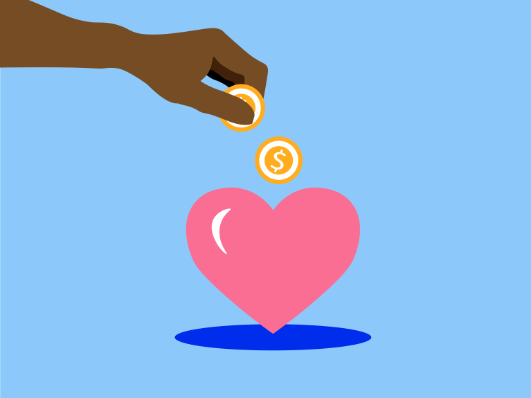 A hand dropping coins into a pink heart shaped coin box against a light blue background.