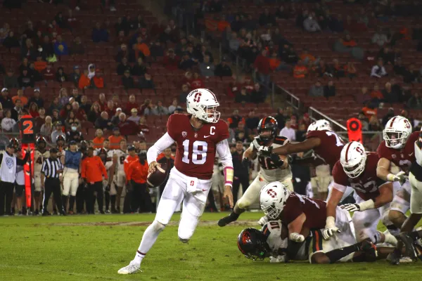 A quarterback runs from the defense