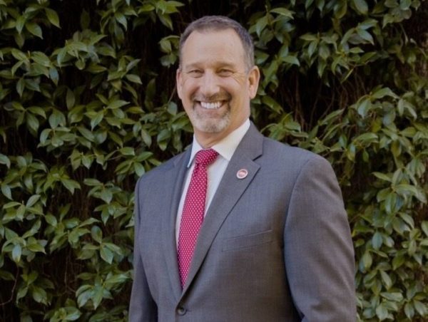 Brian Dahle stands in a suit in front of a green wall