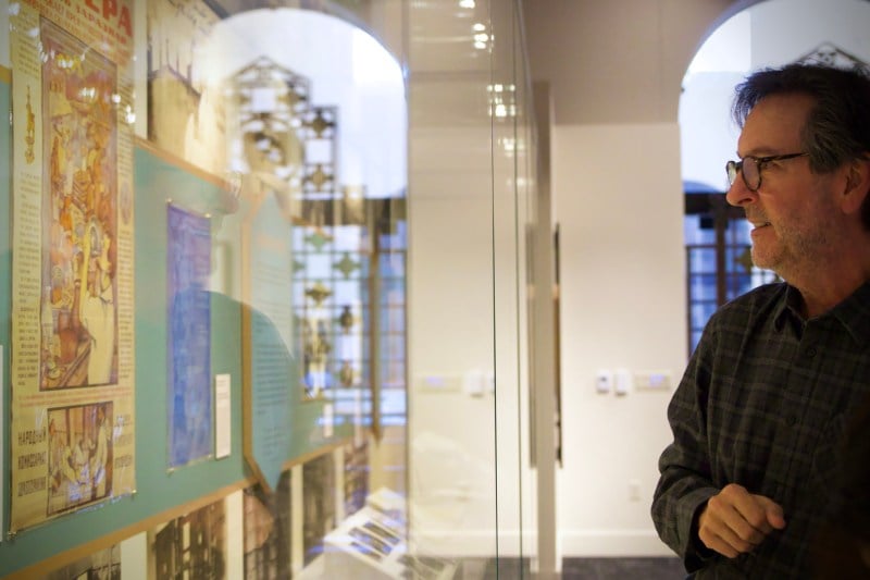 A middle-aged man looks at posters and archived exhibited on the wall