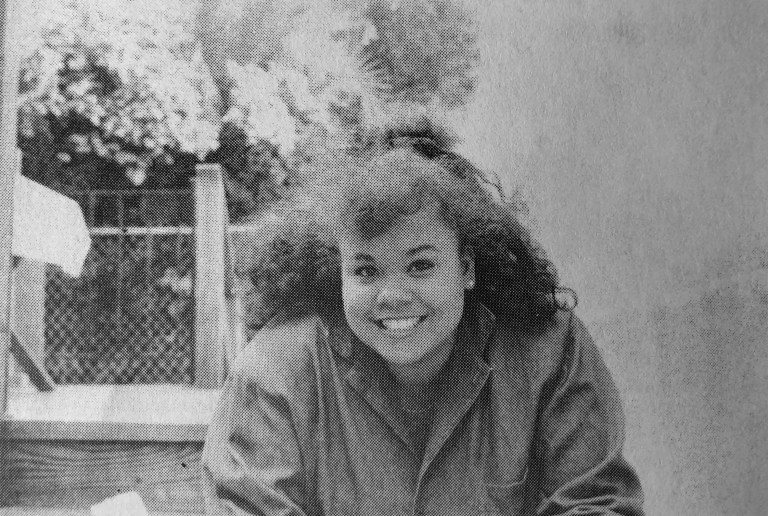 A black and white photograph of Julie-Lythcott-Haims as a senior in 1988, smiling at the camera and wearing a collared jacket