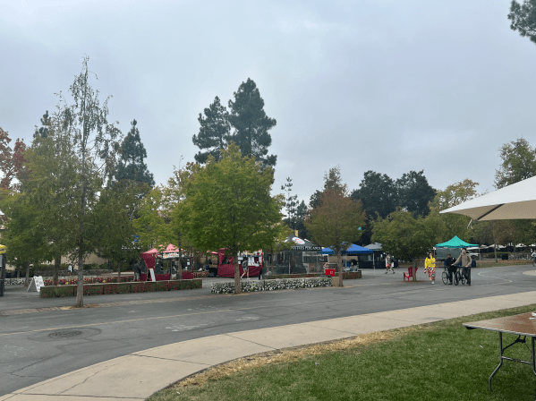 Colorful tents selling food dot White Plaza under green trees and a grey sky