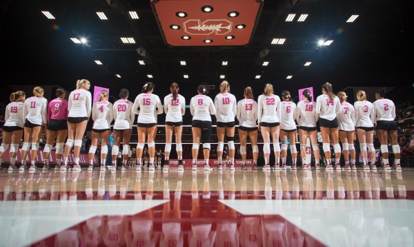 The volleyball team stands for the national anthem.