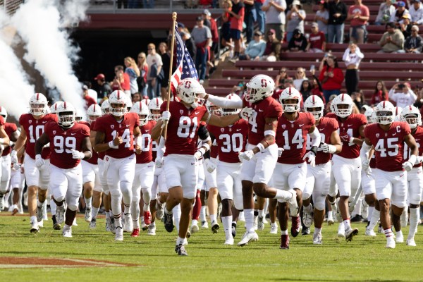 A football team in red jerseys and white helmets runs onto the field