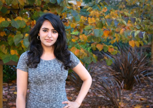 Henna Hundal stands for a portrait in front of a flower bush