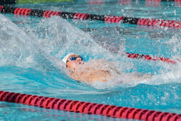 A swimmer is on his back in the pool going breakstroke