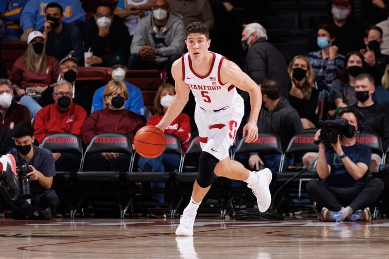 A basketball player looks up the court as he dribbles the ball