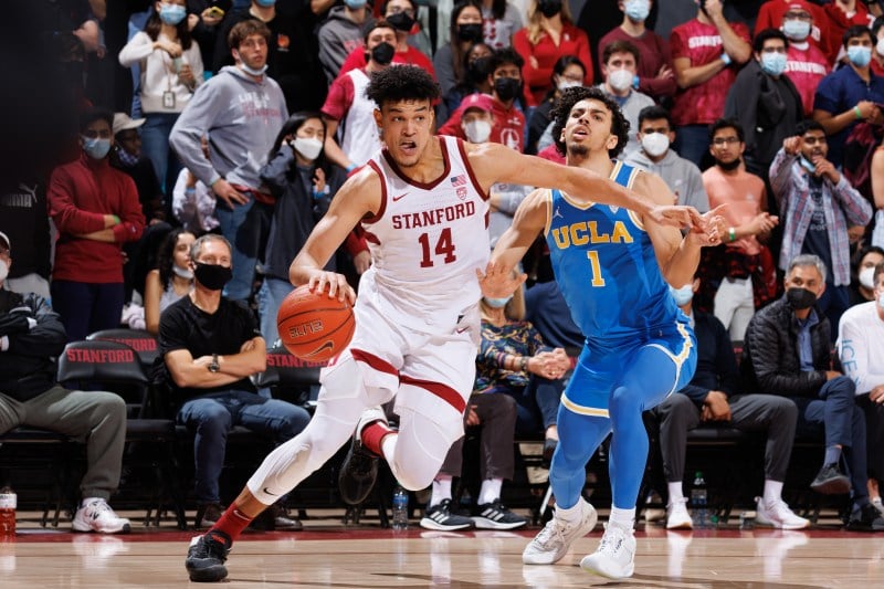 A basketball player drives by his defender towards the basket