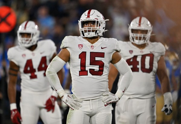 Three football players side by side with their hands on their hips