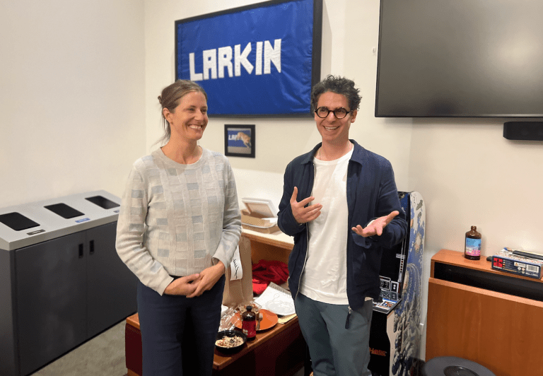 Two people stand in front of a banner that reads "LARKIN"