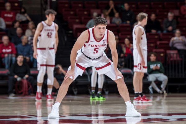 A basketball player in a white uniform hunched over, hands on knees