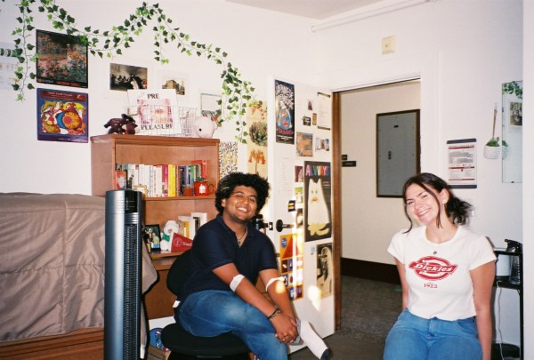 Students sit, smiling in chairs as their room is showcase behind them.