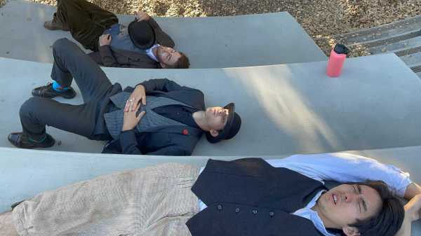 Three actors are lying down, sprawled across three descending stair slabs.