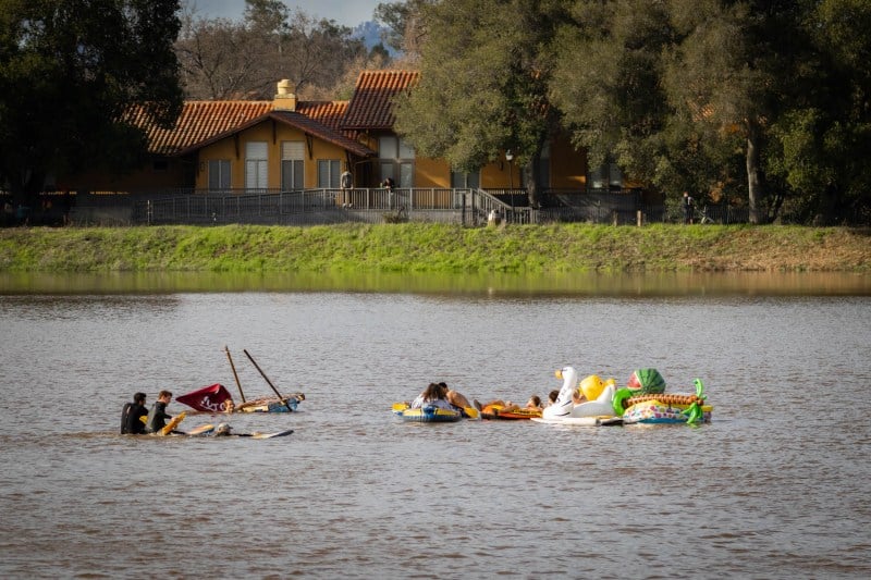 Boats and colorful rubber duck rafts on the lake with the Elliott Program Center in the background.