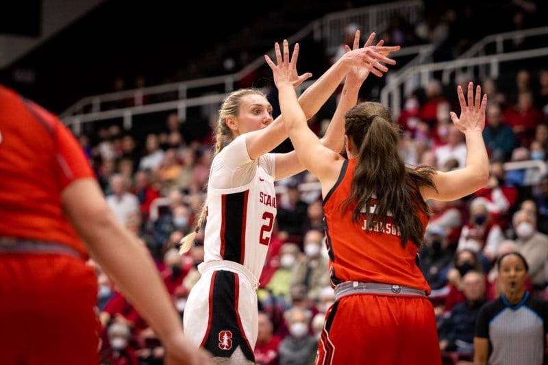 A basketball player shoots as a defender contests