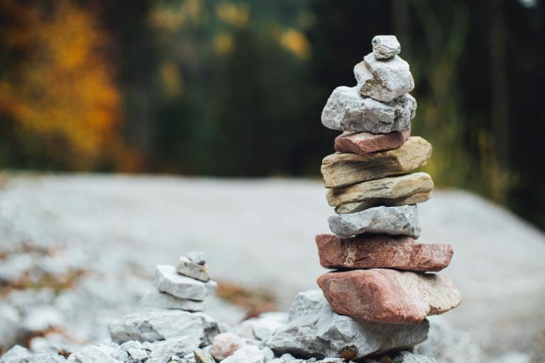 Two stacks of rocks sit next to one another; one is tall than the other.