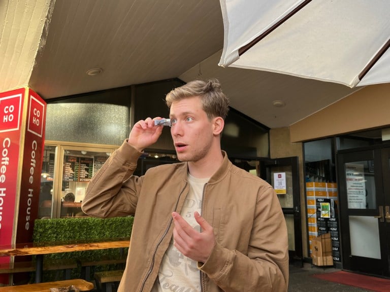 A man demonstrating the use of wearable eyewear technology by placing the technology on his eyes and looking through them