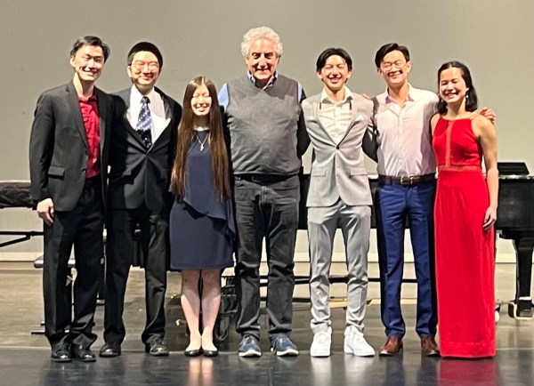 a photo of seven people lined up and smiling on a stage, all dressed in formal or semiformal wear