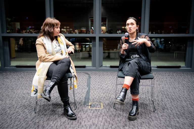 The two stegner fellows laugh in conversation in a brightly lit room