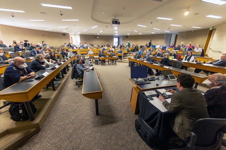 Faculty senators sit in their seats looking toward the center of the room