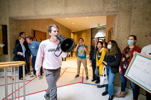 A student with a megaphone walks in front of other students.