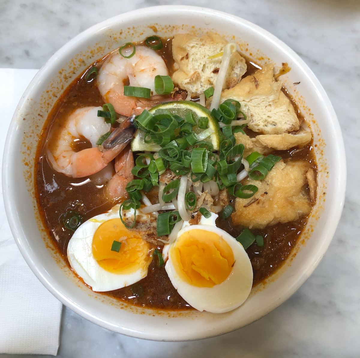 The mee siam noodle dish has a soft boiled egg, shrimp, chives and tofu.