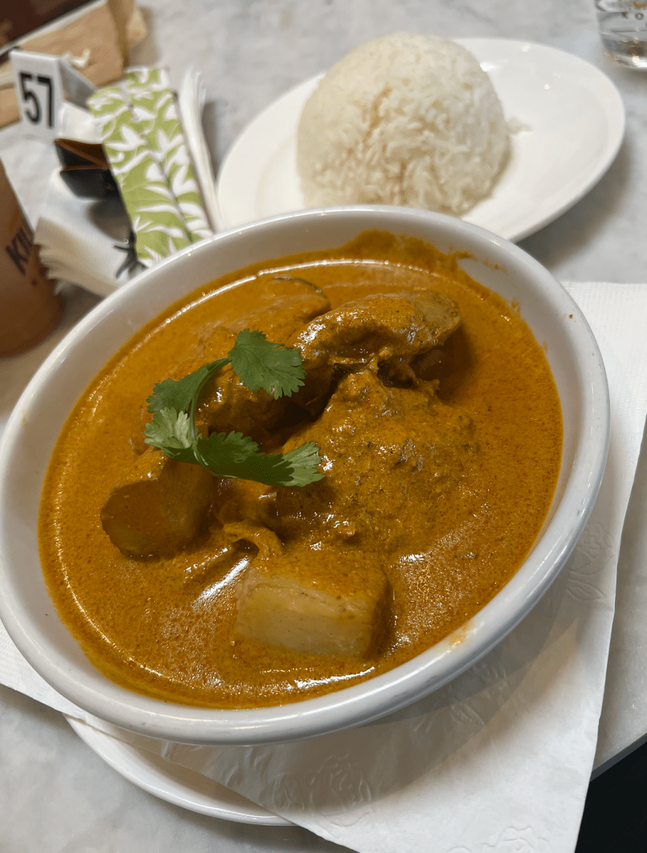 The chicken curry dish displays velvety orange curry in front of a plate of rice.