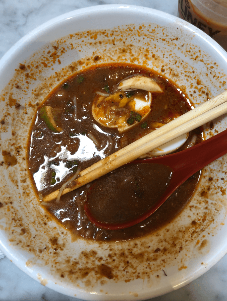 The remains of the mee siam noodle dish sit in a white bowl.