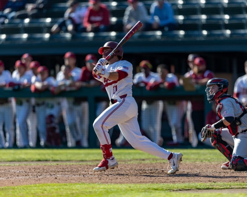 A batter looks at a baseball after hitting it, post swing. 