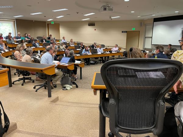 A conference room of people sitting for a formal meeting.