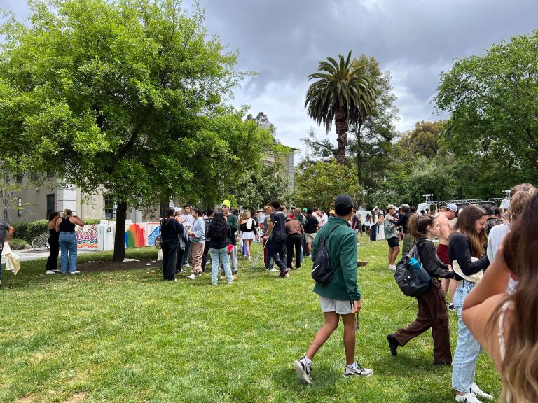 Students mingling in a green lawn on a cloudy afternoon in front of the Sigma Nu house