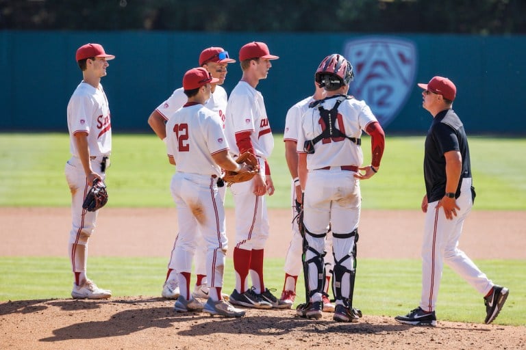 Baseball players stand at the mound