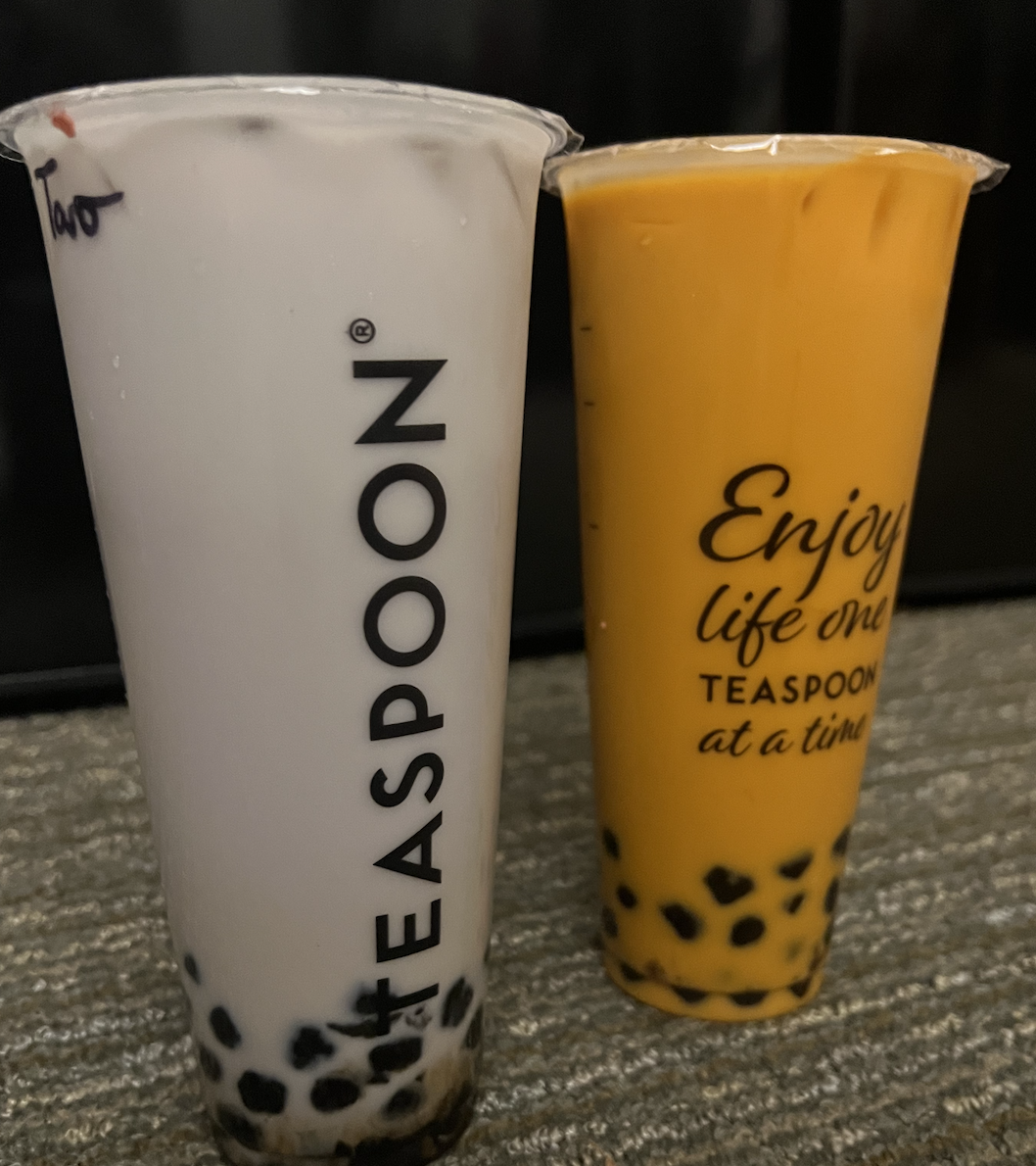 Two drinks from Teaspoon, one taro and one Thai, stand on a couch. 