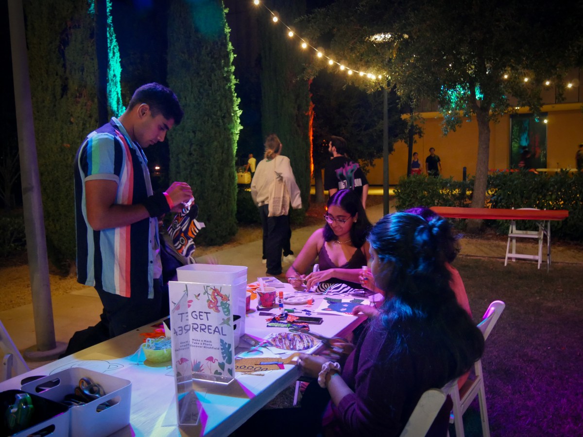 A group of students doing crafts in a dark room lit by string lights.