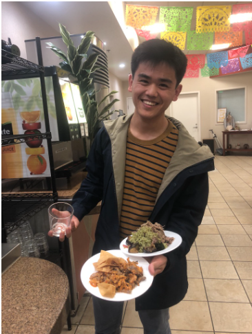 A student balances two plates in one hand while holding a drink with their other hand.