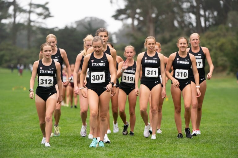 The women's cross country team walks through an open field in uniform